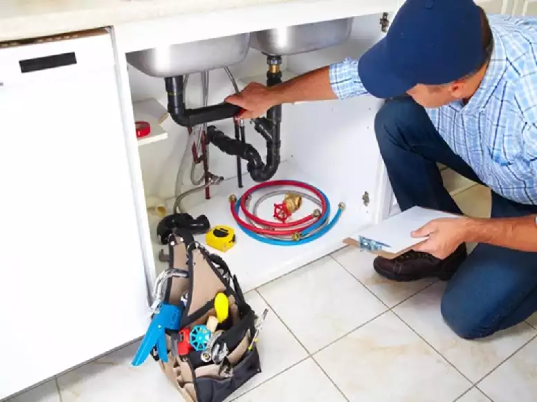 Picture of a plumbing contractor analying the pipes under a kitchen sink 